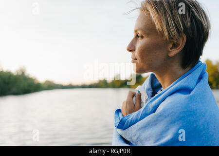 Ritratto di donna avvolta in un asciugamano in un lago Foto Stock