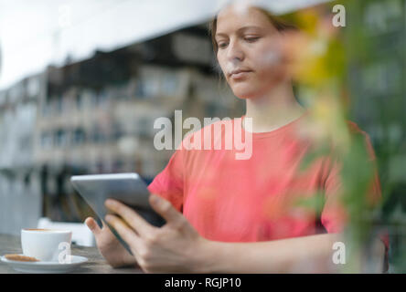 Giovane donna con tavoletta nella finestra in un cafe Foto Stock
