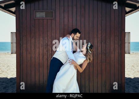 Coppia di sposi godendo momenti romantici nella parte anteriore di una capanna sulla spiaggia Foto Stock