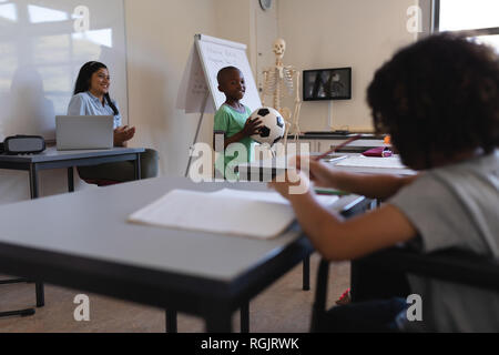 Sorridente schoolboy tenendo il calcio in aula Foto Stock