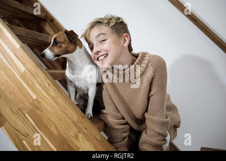 Ritratto di grinning boy e il suo Jack Russel Terrier su scale a casa Foto Stock