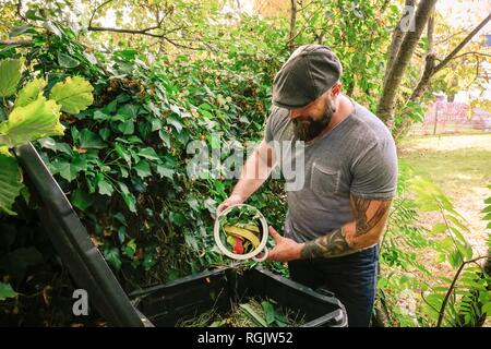 Uomo maturo scartando scarti di cucina sul palo di composto Foto Stock