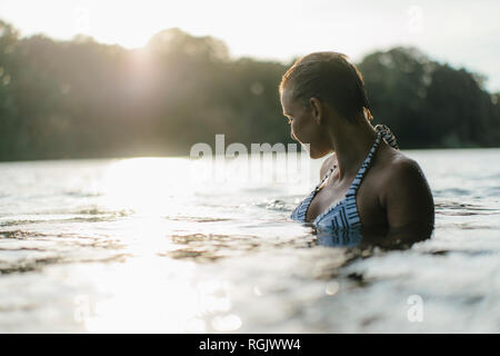 La donna in un lago al tramonto Foto Stock