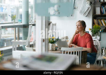 Giovane donna utilizzando laptop a tavola in un cafe Foto Stock