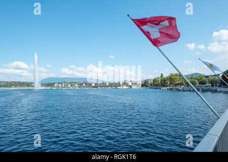 Inclinazione in diagonale nella foto sopra il Lago di Ginevra e una luminosa bandiera rossa con iconica croce bianca vola sopra uno sfondo compresa Ginevra lungomare di un Foto Stock