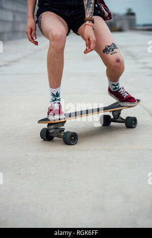 Le gambe della giovane donna cavallo carver skateboard su un lungomare Foto Stock