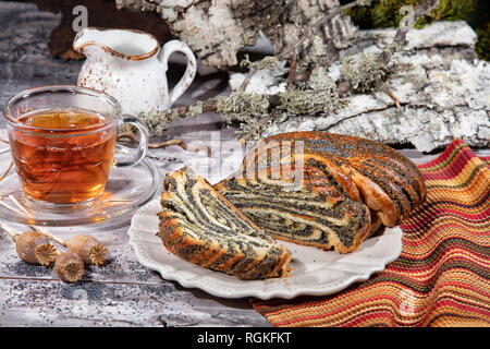 Il papavero pasticceria e una tazza di tè su uno sfondo di tessuto Foto Stock