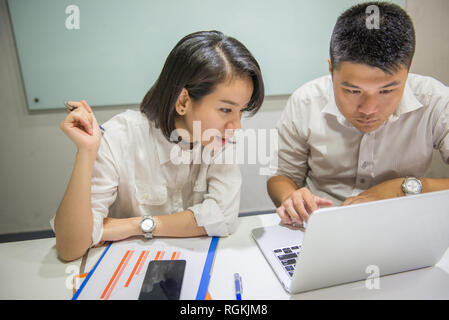Due uffici asiatici dipendenti di lavorare in un team Foto Stock