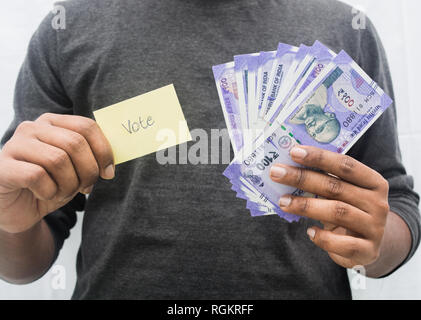 Uomo con denaro e simbolo di voto in mano, concetto di mostra una cassa per votare. Foto Stock