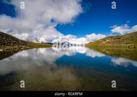 Vista panoramica sul lago ghiacciato, la coperta di neve i vertici della catena Hannapurna in nuvole a distanza Foto Stock