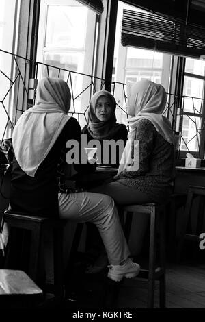 Tre indonesiano donna musulmana discutendo in cafe Foto Stock