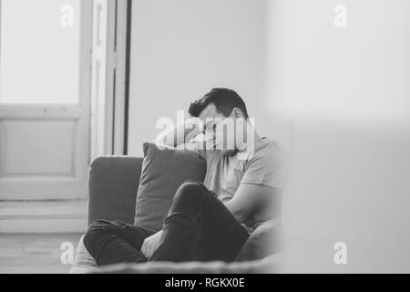 Ritratto di giovane uomo abbattimento premuto e pianto disperato da soli in divano home sofferenza dolore emotivo e di infelicità. Nelle persone cuore spezzato, Bull Foto Stock