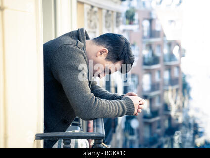 Triste premuto infelice giovane piangendo e suicida sensazione disperata, isolato e inutile staring giù per la strada sul balcone di casa in persone Depres Foto Stock