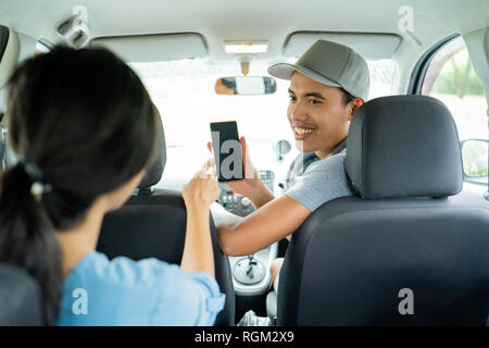 Driver maschio mostra il suo smartphone per approvare il pagamento Foto Stock