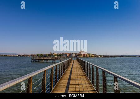 La passerella sul lago di Lesina e la vista del villaggio in background Foto Stock