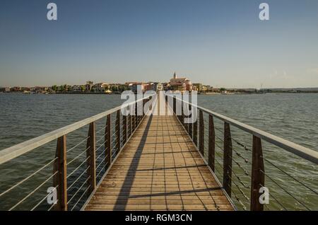 La passerella sul lago di Lesina e la vista del villaggio in background Foto Stock