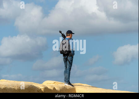 Uomo che indossa uno zaino e il trasporto di un treppiede permanente sulla sommità di rocce calcaree Foto Stock