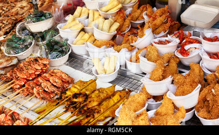Cucina di strada in stallo con i gamberi alla griglia, carne e involtini primavera, il fuoco selettivo. Foto Stock