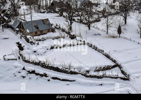 I residenti si vede a piedi attraverso la neve su una soleggiata giornata invernale nella zona Gagangir del distretto Ganderbal, a circa 80km da Srinagar, Indiano Kashmir amministrato. Il Kashmir è il più settentrionale della regione geografica del subcontinente indiano. Attualmente è della contestazione di un territorio amministrato da tre paesi: India, Pakistan e Cina. Foto Stock