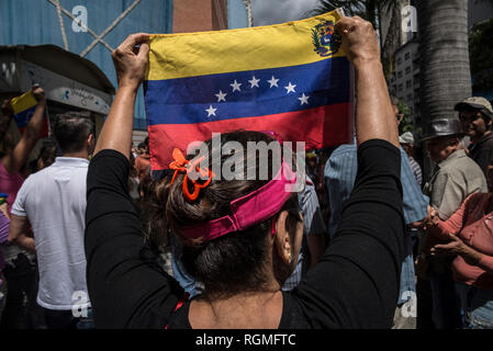 Caracas, Venezuela. 30 gen, 2019. Una donna è in attesa di una bandiera venezuelana in una protesta contro il governo del Capo di Stato Maduro. In mezzo alla lotta di potere tra il governo e l'opposizione, dimostranti contro il controverso capo di stato Maduro hanno nuovamente preso per le strade in Venezuela. Credito: Ivan del Carpio/dpa/Alamy Live News Foto Stock