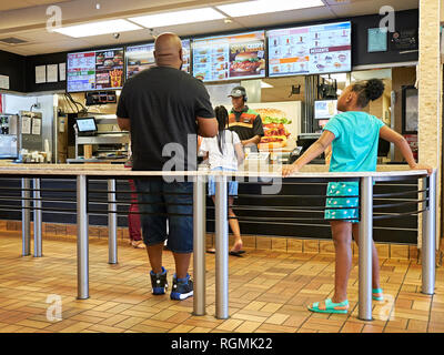 Padre o di uomo e di giovani ragazze essendo servito all'interno in linea ad un Burger King e un ristorante fast food a Montgomery in Alabama, Stati Uniti d'America. Foto Stock