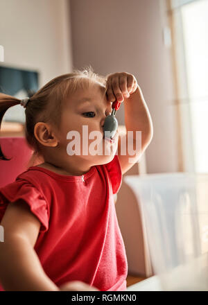 Ritratto di bambina gioca con cucchiaio plasic Foto Stock