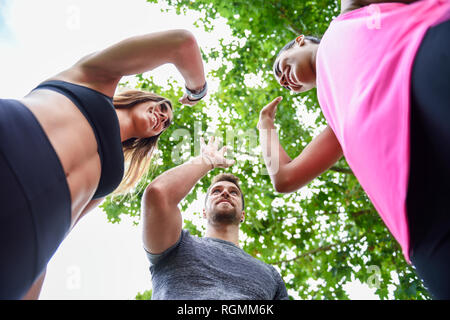 Sport giovane team di alta fiving nel Parco celebrando il successo Foto Stock