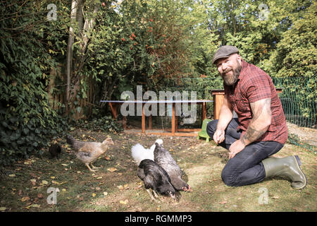 L uomo nel suo giardino, uomo alimentazione di polli ruspanti Foto Stock