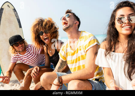 Amici seduti sulla spiaggia, divertimento Foto Stock