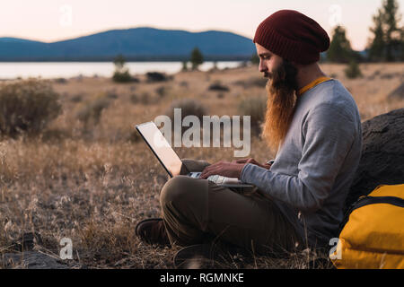 Stati Uniti d'America, a nord della California, barbuto giovane uomo utilizzando laptop vicino Parco Nazionale vulcanico di Lassen Foto Stock
