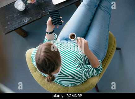 Vista aerea del giovane donna con un telefono cellulare ed espresso in un cafe Foto Stock