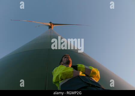 Basso angolo di visione dell'ingegnere in piedi in una turbina eolica Foto Stock