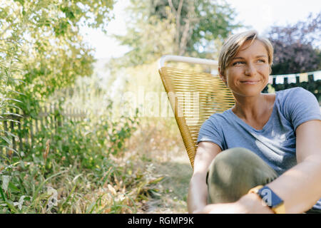 Donna seduta nel giardino sulla sedia Foto Stock