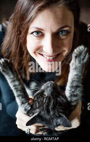 Ritratto di donna sorridente e il suo grigio tabby cat Foto Stock