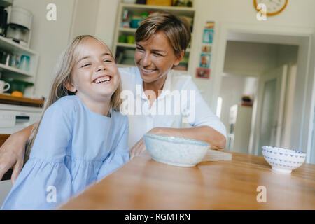 Felice madre e figlia seduti al tavolo della cucina a casa Foto Stock