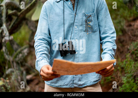 Giovane uomo in piedi in natura, guardando alla mappa Foto Stock