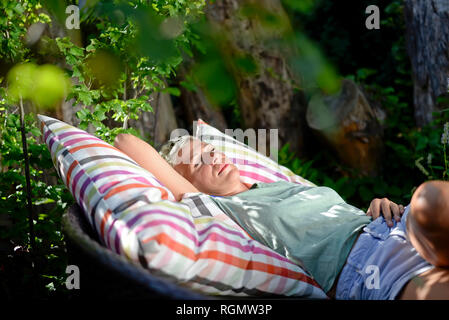 Donna relax su grande cuscino in giardino Foto Stock