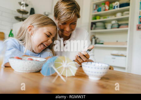 Felice madre e figlia divertirsi a tavola in casa Foto Stock