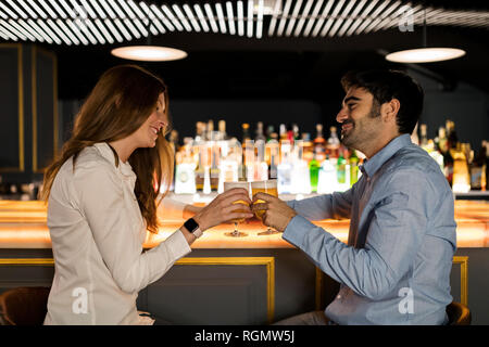 Coppia sorridente il tintinnio dei bicchieri in un bar Foto Stock