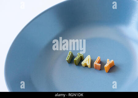 La parola "l'Italia" composta con pasta reale lettere in bandiera italiana i colori in un piatto blu. Sfondo con copia spazio sulla sinistra. Foto Stock