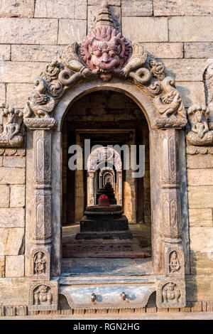 Vista attraverso le porte di molti piccoli templi a ghats del fiume Bagmati al tempio di Pashupatinath Foto Stock