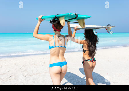 Gli amici di andare a fare surf, portando le tavole da surf sulla parte superiore delle teste Foto Stock