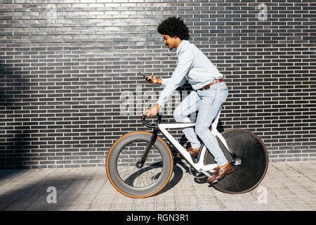 Metà uomo adulto in sella alla sua bicicletta, utilizza lo smartphone Foto Stock