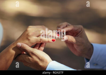 Lo sposo di mettere l'anello nuziale sul dito della sposa, close up Foto Stock