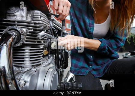 Close-up di giovane donna a lavorare sulla moto Foto Stock