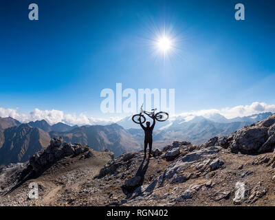 La regione di bordo Italia Svizzera, allietarla uomo con mountainbike sul picco del Piz Umbrail Foto Stock