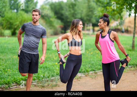 I giovani atleti facendo si allunga la gamba in un parco Foto Stock