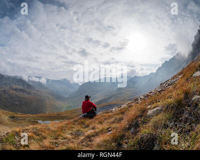 La regione di bordo Italia Svizzera, senior uomo avente una pausa dalle escursioni nel paesaggio di montagna al Piz Umbrail Foto Stock