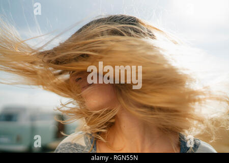 Blong giovane donna a camper van scuotendo i suoi capelli Foto Stock