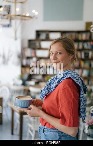 Ritratto di sorridente giovane donna che serve caffè in un bar Foto Stock